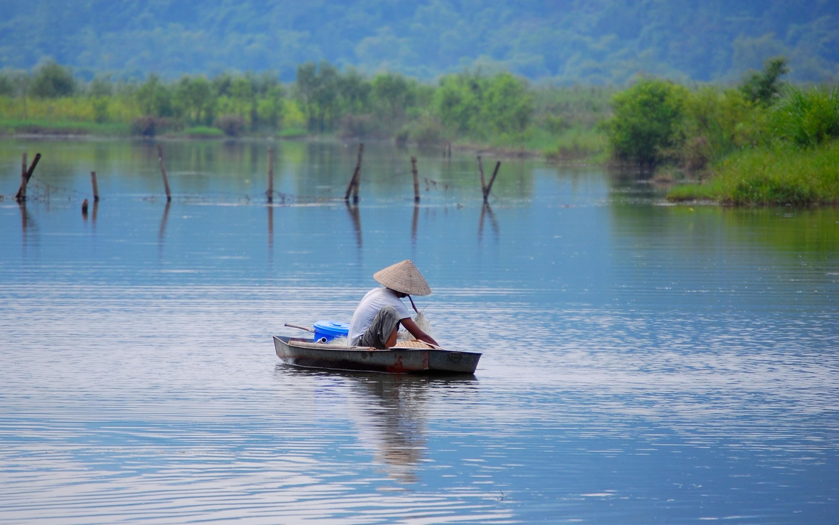 Two men fishing from small boat with net and paddle Yen River leading to  Perfume Pagoda near Hanoi north Vietnam Stock Photo - Alamy